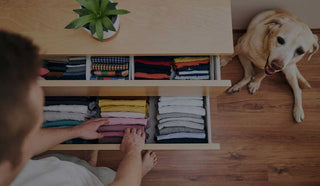 Image of man organizing his drawer while his dog looks at him 