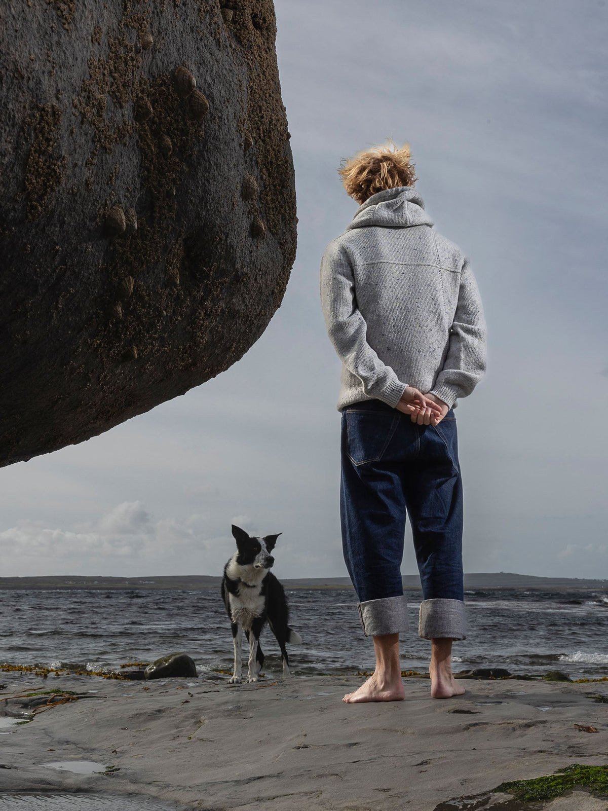 Inis Meáin merino cashmere hoodie in silver fleck, arms out against a blue sky