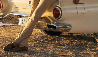 Picture of man at the beach reclining against the trunk of his car, wearing Allen Edmonds shoes