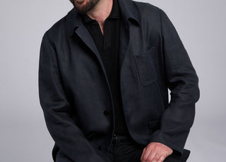Man wearing a black coat and pants against a gray background