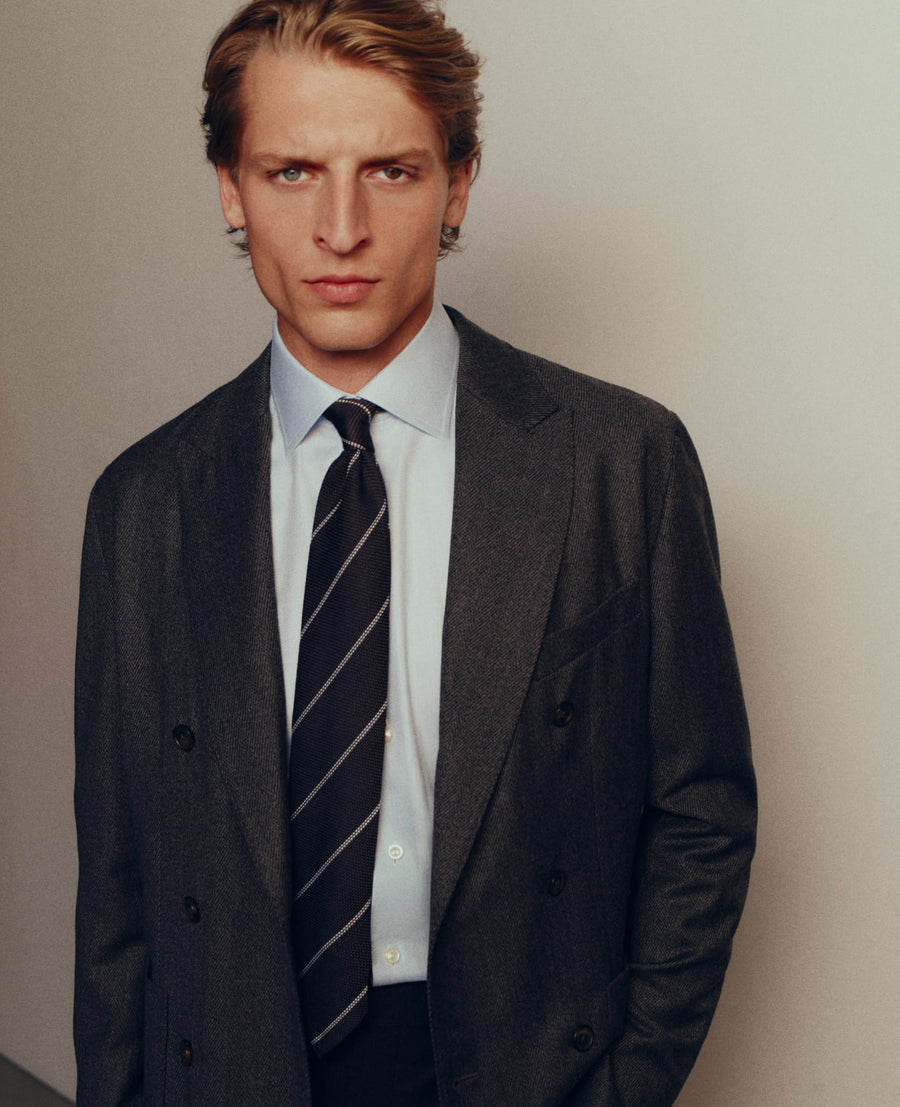 A light blue Eton shirt and striped tie under a double-breasted jacket