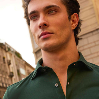 A man in a green Sonrisa shirt on a city street
